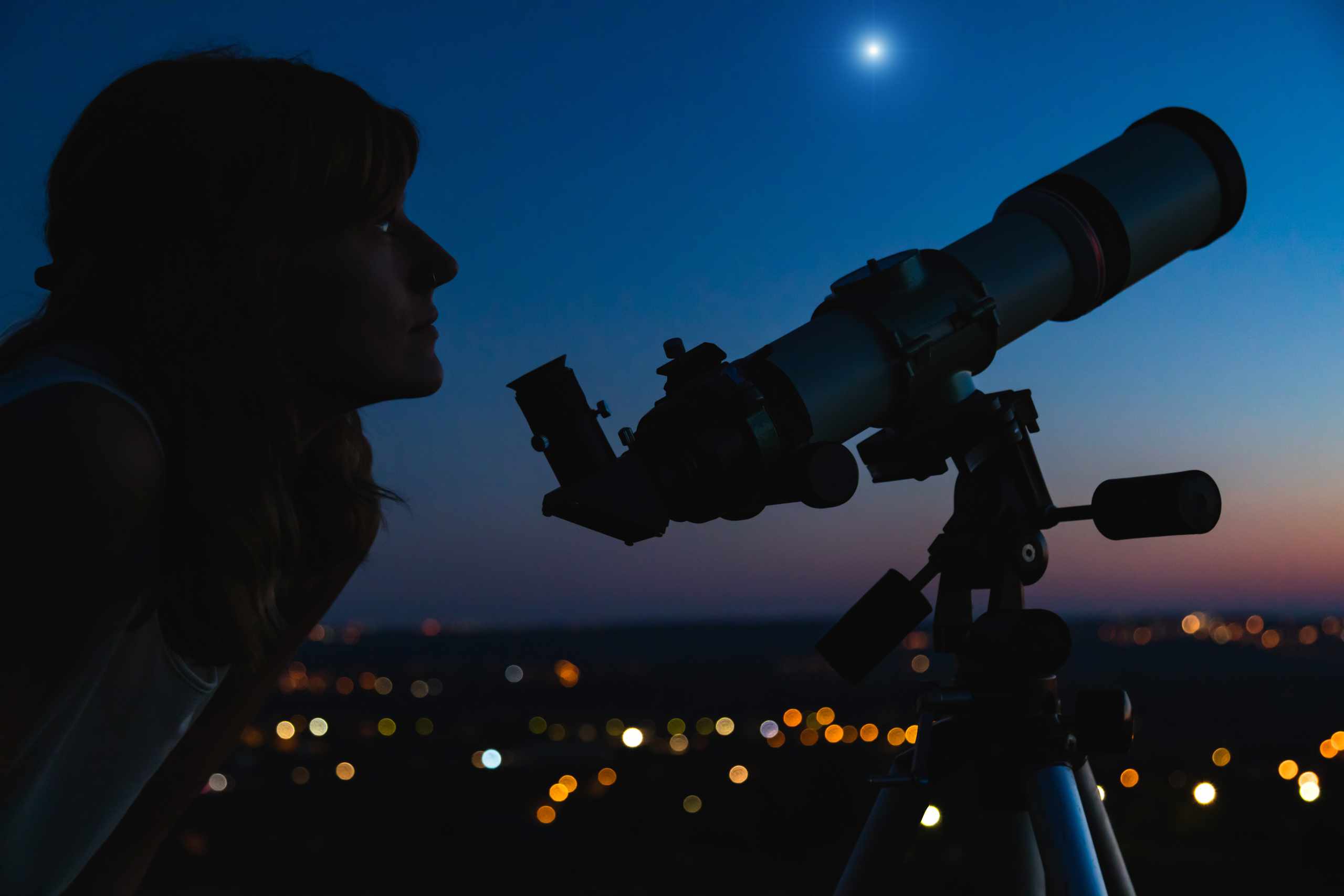 Woman observing the night sky through a telescope